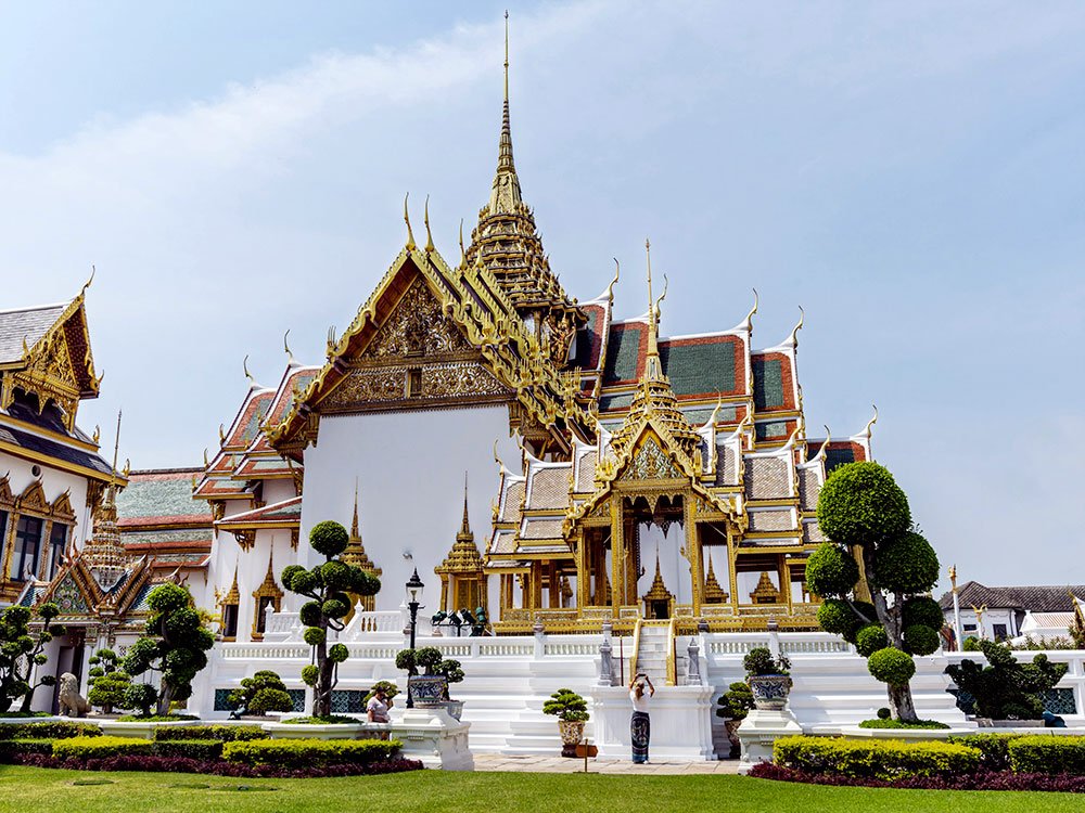 The Grand Palace in Bangkok featuring golden stupas under a bright blue sky